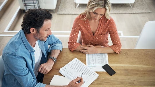 Man and woman sit at table reviewing documents.